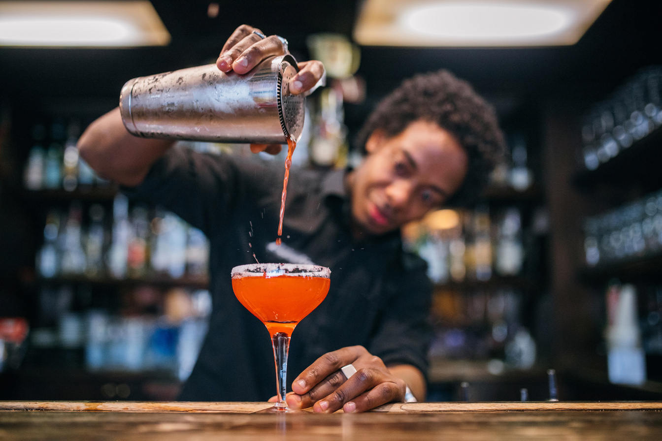 Young bartender pouring cocktails in a cocktail bar
