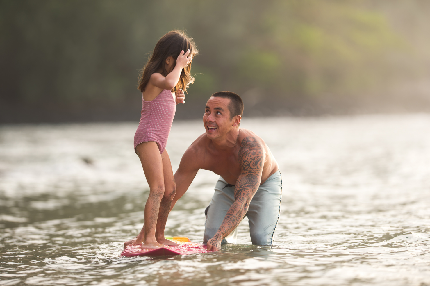 Eurasian dad teaches his lilttle girl how to surf